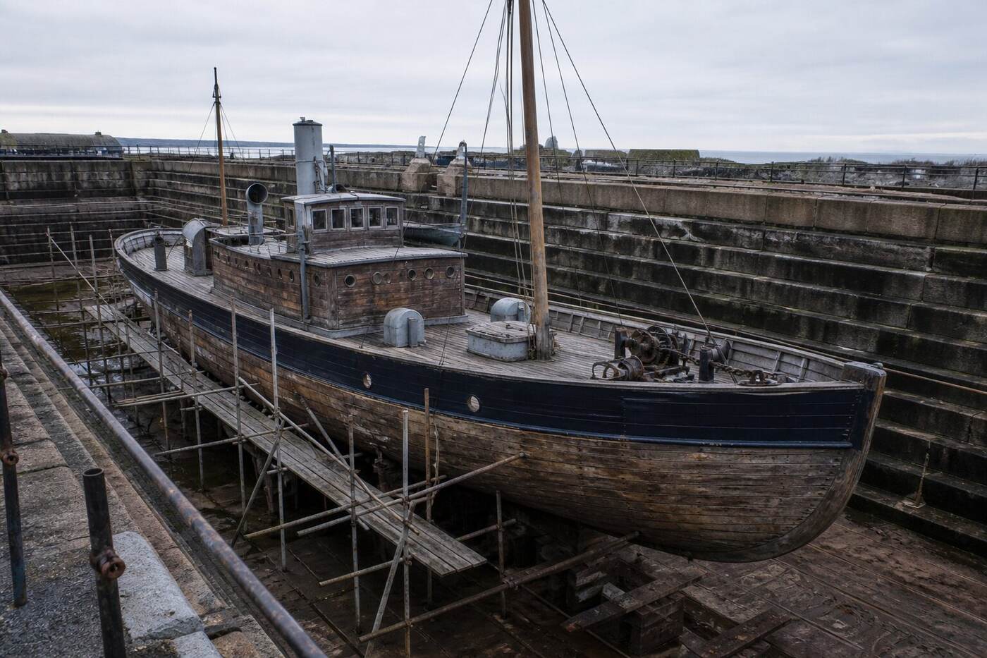 A small wooden minesweeper resting in a quiet dry dock